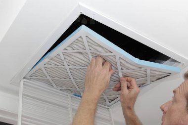 Adam kaldırma kirli hava filtresi, bir eski kirli hava kaldırma kişi bir ev Hvac sistemi tavan alımı havalandırma filtre. Tavan havalandırma dışarı atılıyor kirli gri kare fırın hava filtresi.
