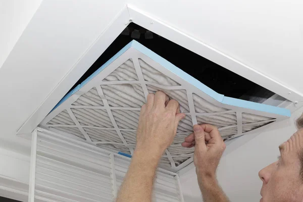 Adam kaldırma kirli hava filtresi, bir eski kirli hava kaldırma kişi bir ev Hvac sistemi tavan alımı havalandırma filtre. Tavan havalandırma dışarı atılıyor kirli gri kare fırın hava filtresi.