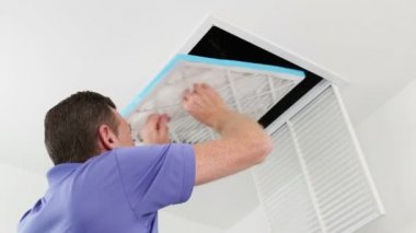 Kişi inceleyerek Hvac kanalı ile bir Flashlightmale tavan hava filtresi kaldırır, bakım için kanalları inceliyor ve hava filtresi yerini alır. Adam bir ev tavan hava kanalı teftiş bir el feneri ile