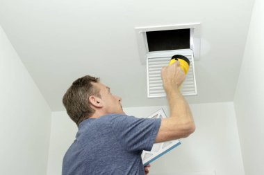 Hava kanalları ev Hvac sistemi denetleniyor. Bir el feneri nakli boru küçük kare tavan vantilatör ile parlayan hava kanalları teftiş adam. Olgun erkek hava kanalları evde durumunu inceleyerek.