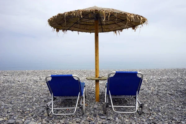 Şemsiye Çakıl Plajı Üzerinde Iki Yatak — Stok fotoğraf