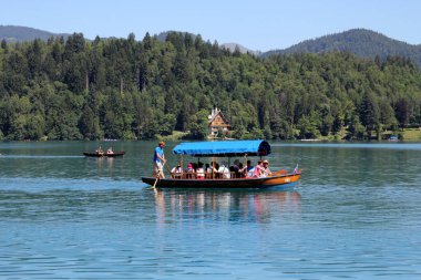 Bled Gölü 'ndeki Tahta Turist Teknesi, Bled Castle' a çok uzak değil. Bled Castle bir ortaçağ kalesi, Slovenya 'nın en eski şatosu ve şu anda Slovenya' nın en çok ziyaret edilen turizm merkezlerinden biri..