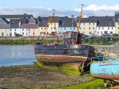 Galway, İrlanda - 3 Ağustos 2018: Bir eski balıkçı teknesi nehir Corrib Galway İrlanda, Claddagh alanında geleneksel evleri Long Walk meşhur Caddesi astar bir fon ile yanındaki