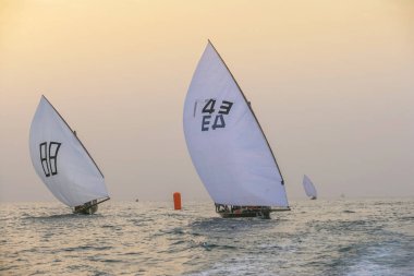 DUBAI, UAE - DECEMBER 16, 2004: Traditional racing dhows crossing the finishing line off Dubai at sunset.