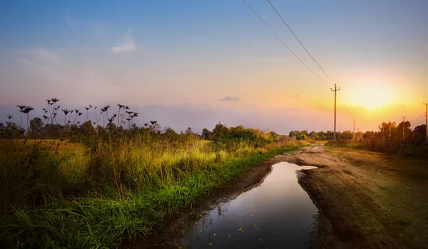 Camino de tierra otoñal en el campo de cultivo después de la lluvia; coun otoño — Foto de Stock