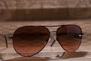 ahşap bir paspas üzerinde yatan kahverengi güneş gözlüğü