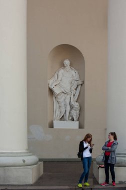 Vilnius, Litvanya - 11 Eylül 2016: İki kimliği belirsiz kadın Evangelist, Vilnius Katedrali Basilica Saint Mark heykeli önünde stand.