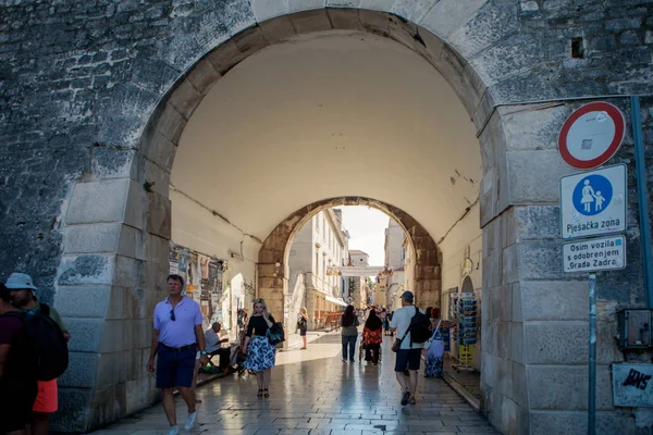 クロアチアのザダル 2017年8月17日 観光客はクロアチアのザダルにお土産店があるメインストリートまで旧市街の門の下を歩く — ストック写真