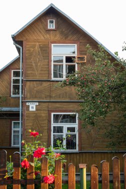 Vilnius, Lithuania - September 2, 2025: Historic wooden residential house with decorative facade and blooming garden in Zirmunai district, showcasing traditional urban architecture heritage.