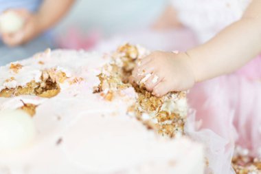 Baby's hand smashing into a cake during a first birthday celebration, a joyful tradition filled with laughter, family love, and unforgettable childhood memories