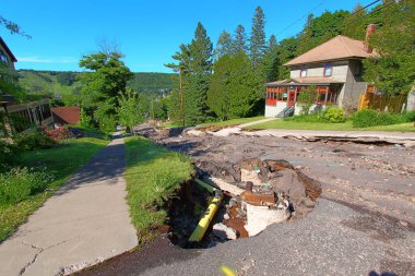 Houghton, Michigan, USA - June 18, 2018: Intense storm rainfall and flash flooding in June of 2018 exposed numerous sinkholes and washed out Agate Street in the town of Houghton, Michigan. clipart