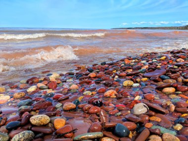 Waves wash up brightly colored rocks along the shoreline of Lake Superior at Porcupine Mountains Wilderness State Park Michigan clipart