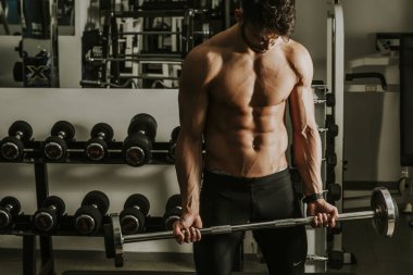 Güçlü ve yakışıklı bir genç adam dumbbells ile egzersiz yaparak portresi