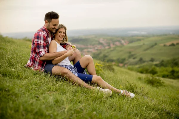 山の草を抱きしめて座ってカップルを愛する — ストック写真