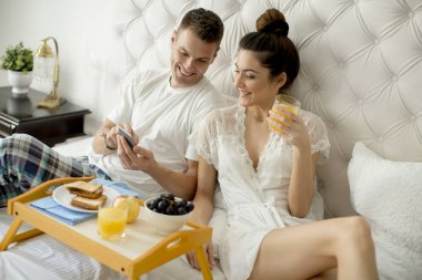 Genç sevgili çift yatakta kahvaltı