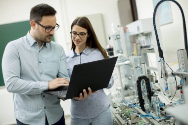 Laptop ile robotik laboratuarda çalışan öğrencilerin genç çift