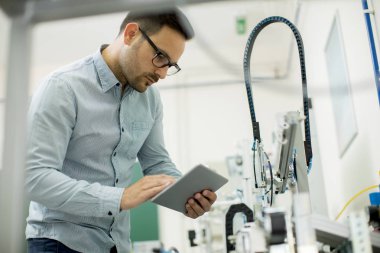 Dijital tablet kullanarak elektronik atölyesinde yakışıklı genç adam portresi