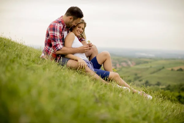 爱的情侣坐在山上的草地上拥抱着 — 图库照片
