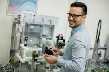 Dijital tablet kullanarak elektronik atölyesinde yakışıklı genç adam portresi