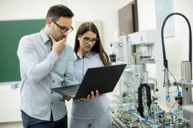 Laptop ile robotik laboratuarda çalışan öğrencilerin genç çift