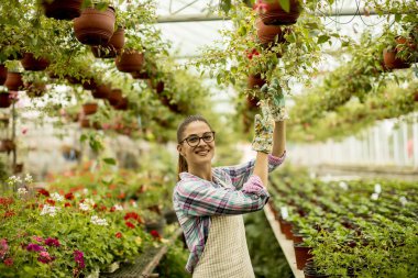 Sera içinde bahar çiçekleri ile çalışan genç ve güzel kadın