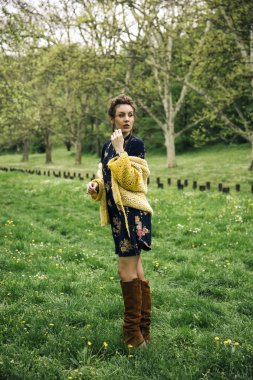 Modern kazak giyen ve parkta poz genç kadın