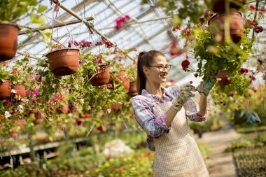 Sera içinde bahar çiçekleri ile çalışan genç ve güzel kadın