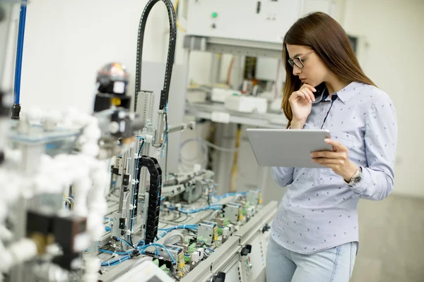 Portrait of young female student of robotics stands in a lab with digital tablet