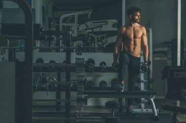 Güçlü ve yakışıklı bir genç adam dumbbells ile egzersiz yaparak portresi