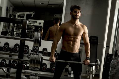 Güçlü ve yakışıklı bir genç adam dumbbells ile egzersiz yaparak portresi