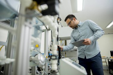 Dijital tablet kullanarak elektronik atölyesinde yakışıklı genç adam portresi