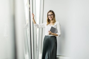 Genç çekici kadın Yöneticisi duran modern Office dijital tablet üzerinde çalışan