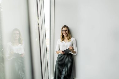 Genç çekici kadın Yöneticisi duran modern Office dijital tablet üzerinde çalışan