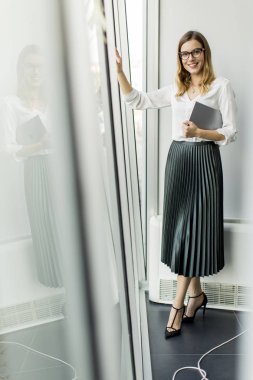 Genç çekici kadın Yöneticisi duran modern Office dijital tablet üzerinde çalışan