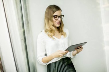 Genç çekici kadın Yöneticisi duran modern Office dijital tablet üzerinde çalışan