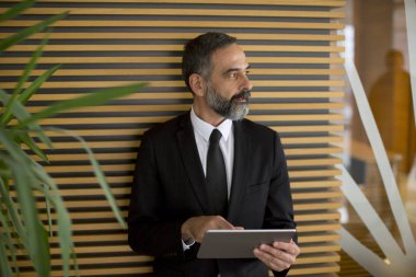 Yakışıklı orta yaş işadamı saatlerin Office dijital tablet ile