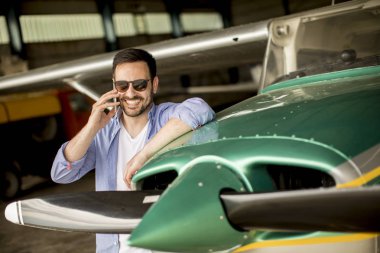 Yakışıklı genç pilot hangarda uçak kontrol