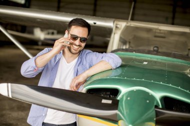 Yakışıklı genç pilot hangarda uçak kontrol