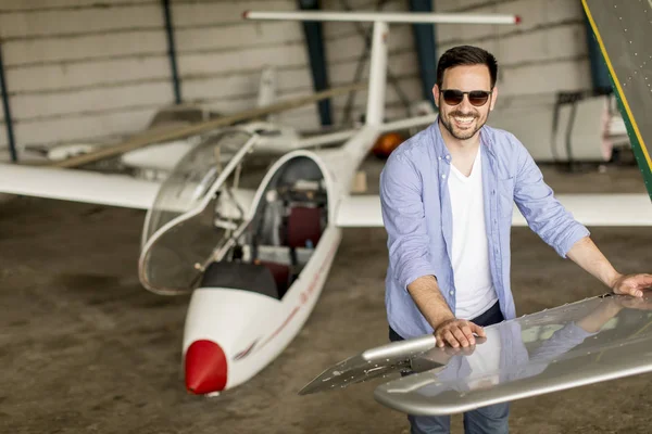 Yakışıklı genç pilot hangarda uçak kontrol
