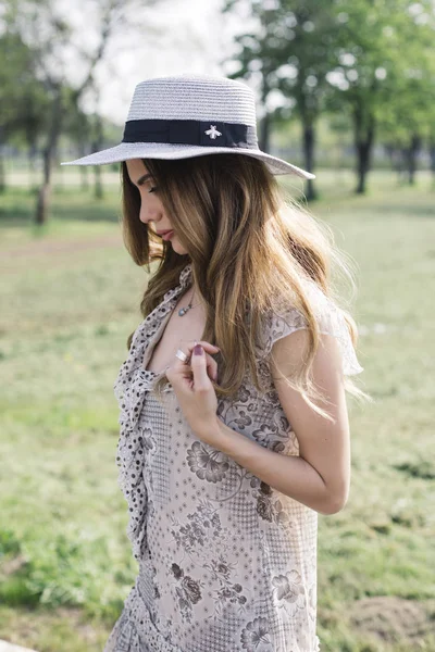 日当たりの良い夏の日に公園でポーズをとって帽子と美しいエレガントな女性のポートレート — ストック写真