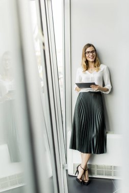 Genç çekici kadın Yöneticisi duran modern Office dijital tablet üzerinde çalışan