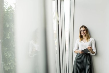 Genç çekici kadın Yöneticisi duran modern Office dijital tablet üzerinde çalışan