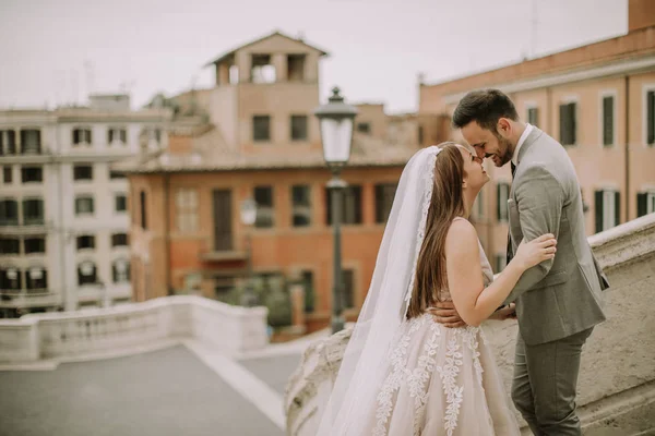年轻迷人的新婚夫妇摆在罗马与美丽和古老的建筑背景 — 图库照片