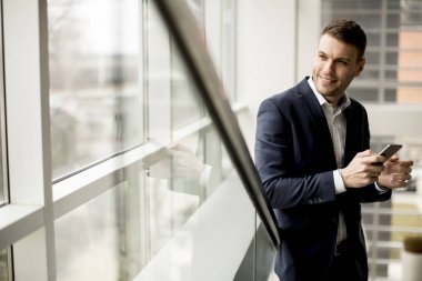 Ofiste akıllı telefon kullanan yakışıklı bir iş adamı.