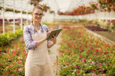 Bahar gününde çiçek bahçesinde dijital tablet ile genç ve güzel kadın