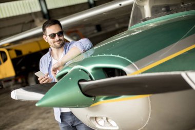 Yakışıklı genç pilot uçuş öncesi hangarda onun ultralight uçak kontrol