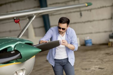 Yakışıklı genç pilot uçuş öncesi hangarda onun ultralight uçak kontrol