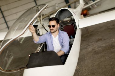 Yakışıklı genç pilot uçuş öncesi hangarda onun ultralight uçak kontrol