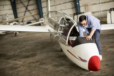 Yakışıklı genç pilot uçuş öncesi hangarda onun ultralight uçak kontrol