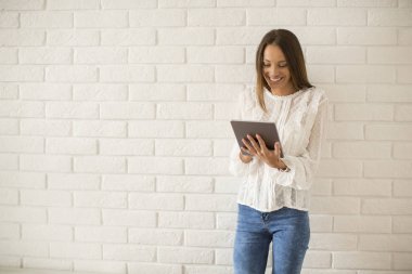 Genç ve güzel kadın tarafından beyaz duvar dijital tablet kullanma